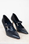Pair of navy high-heeled shoes with a strap on a light background