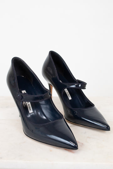 Pair of navy high-heeled shoes with a strap on a light background