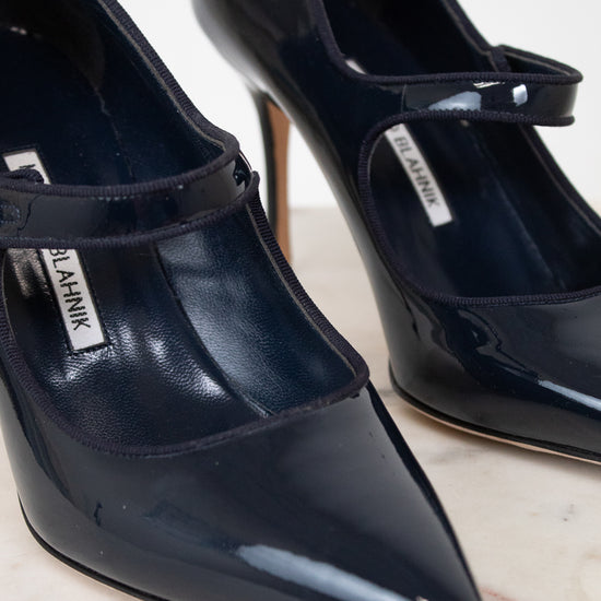Navy patent high-heeled shoes with a brand label on a light background
