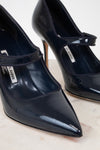 Navy patent high-heeled shoes with a brand label on a light background