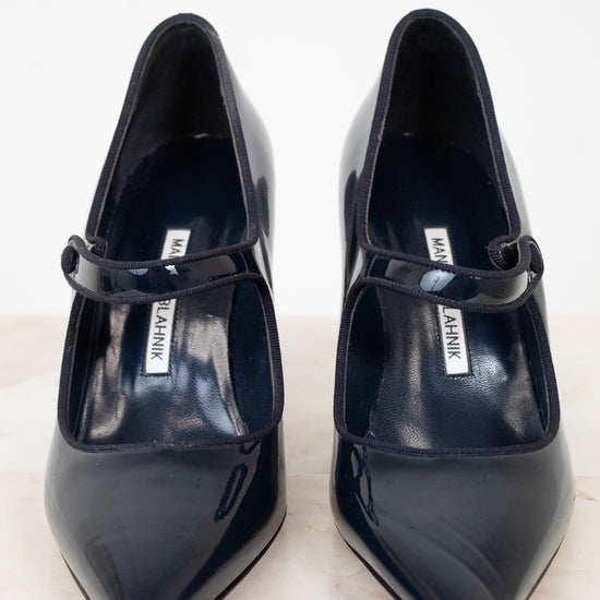 Pair of navy high-heeled shoes with a brand label on a light background