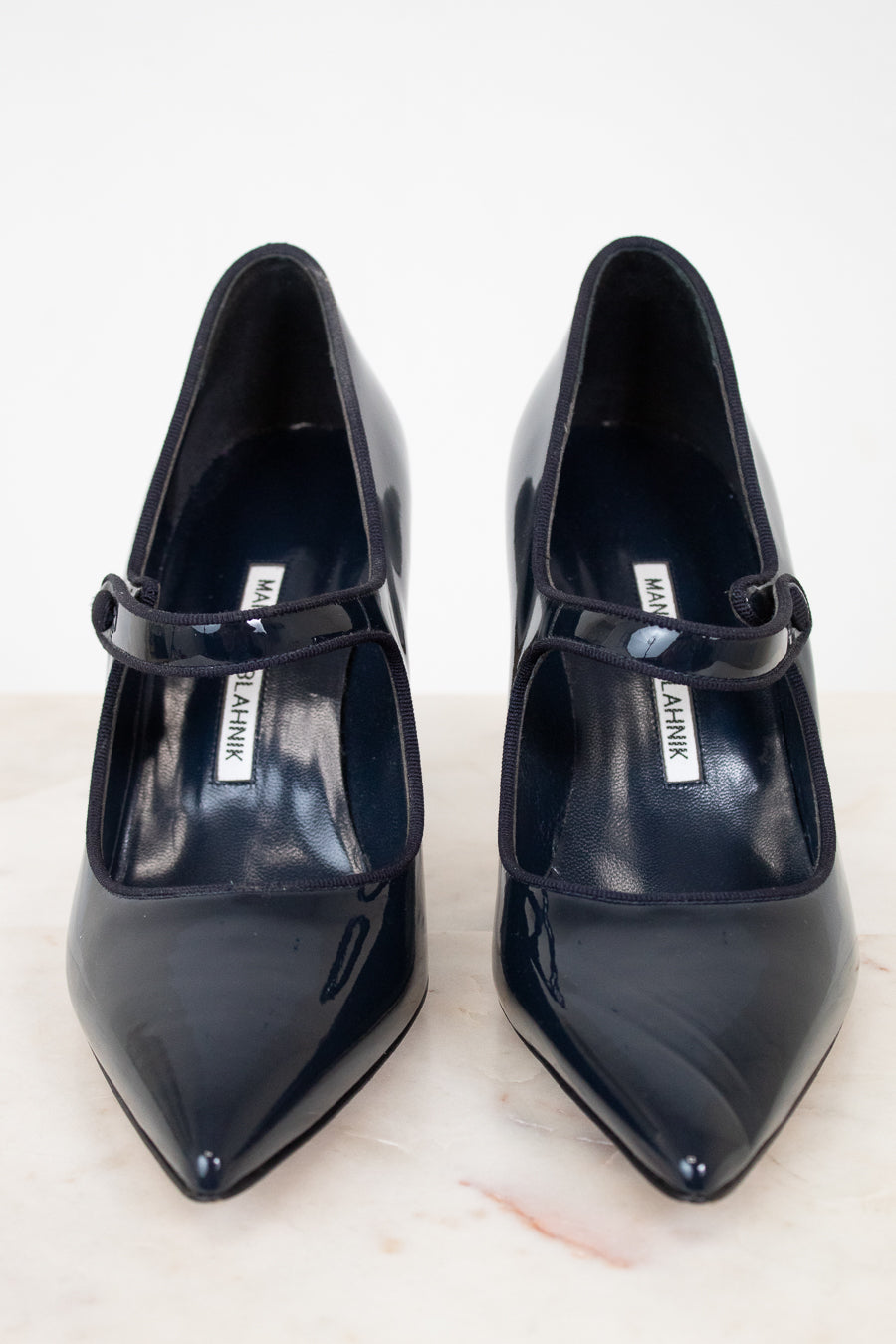 Pair of navy high-heeled shoes with a brand label on a light background