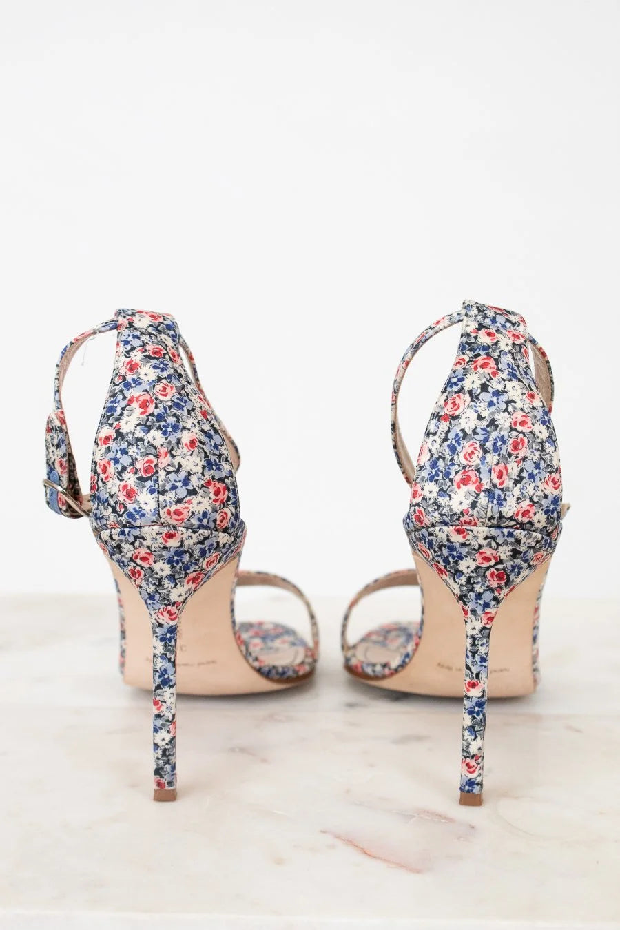 Pair of floral high-heeled shoes on a white background
