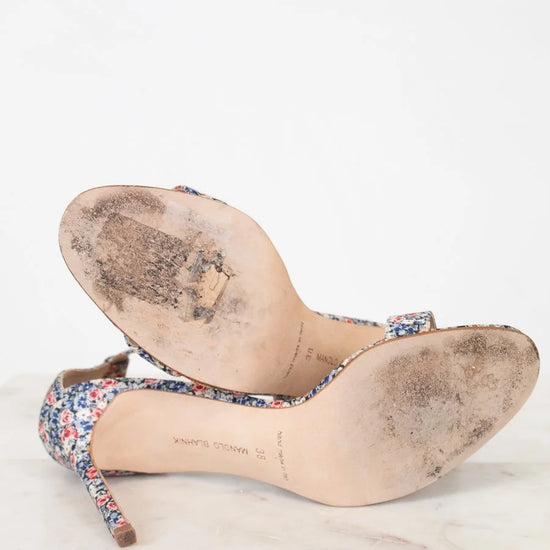 Pair of worn high-heeled shoes with floral pattern on a white background