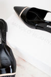 Black high-heeled shoes with 'Manolo Blahnik' branding on a white surface.
