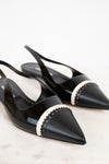 Black pointed-toe shoes with beige accents on a light background