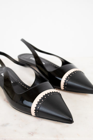 Black pointed-toe shoes with beige accents on a light background