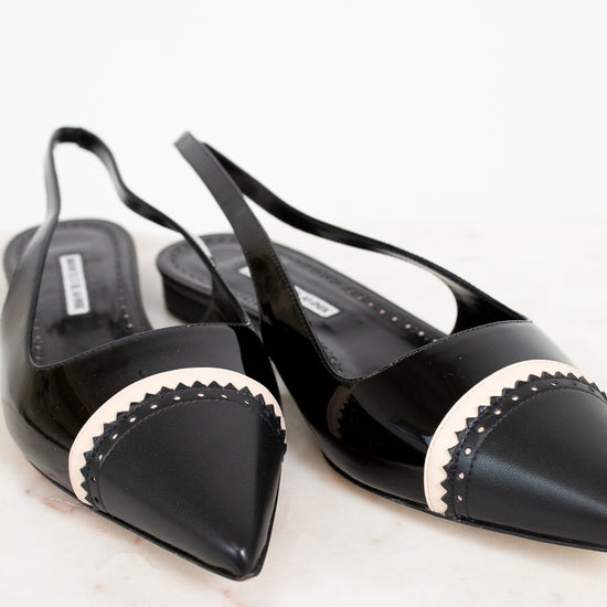 Black pointed-toe slingback shoes with white trim on a light background