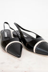 Black pointed-toe slingback shoes with white trim on a light background