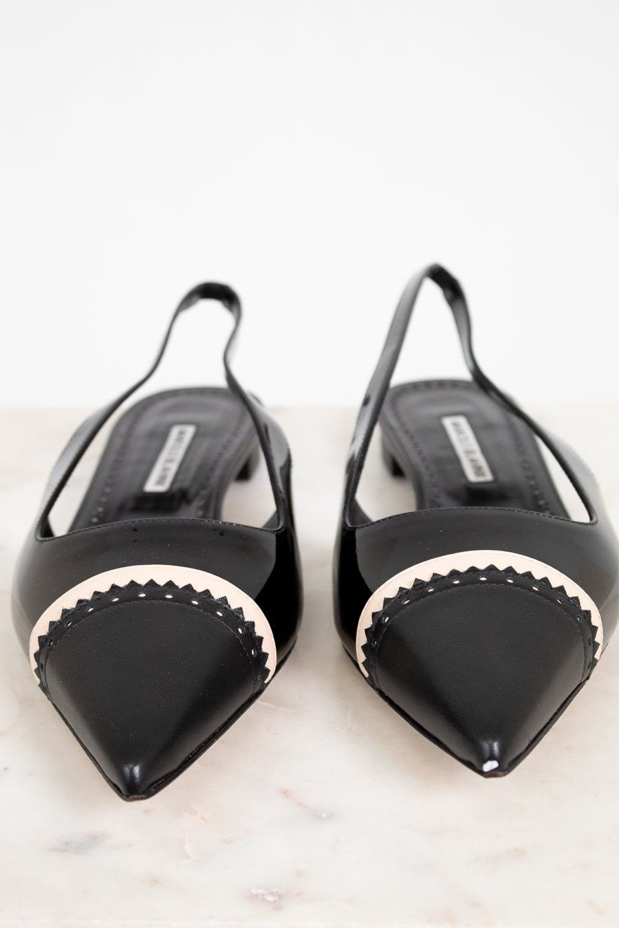 Black flat shoes with pointed toes on a light background