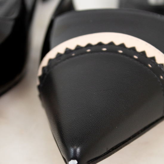 Close-up of a black shoes with beige trim on a light background