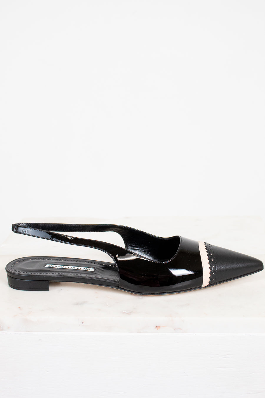 Black patent leather slingback shoes with a pointed toe on a white background