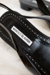 Black high-heeled shoe with 'Manolo Blahnik' label on a marble surface