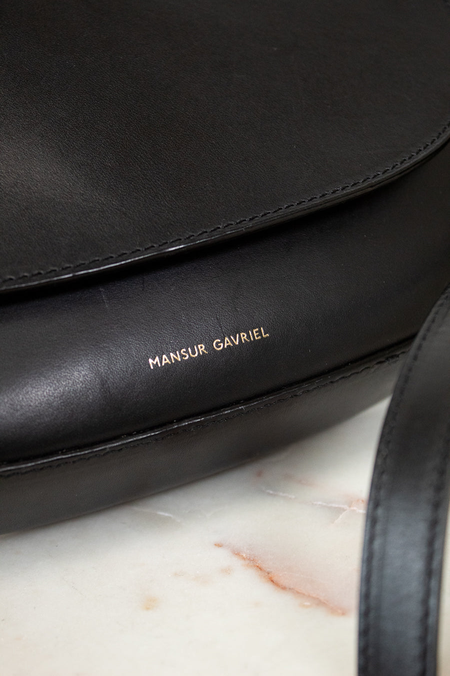 Black handbag with 'Mansur Gavriel' branding on a marble surface