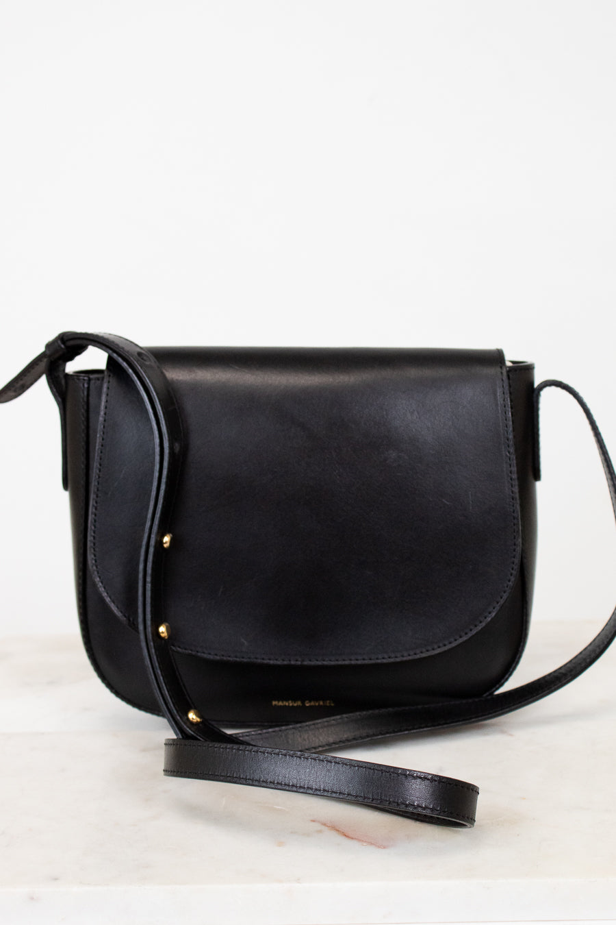 Black leather crossbody bag on a light gray background