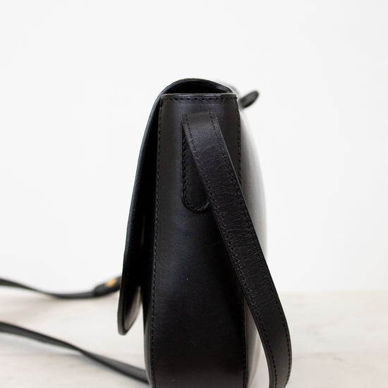 Black leather crossbody bag on a light gray background