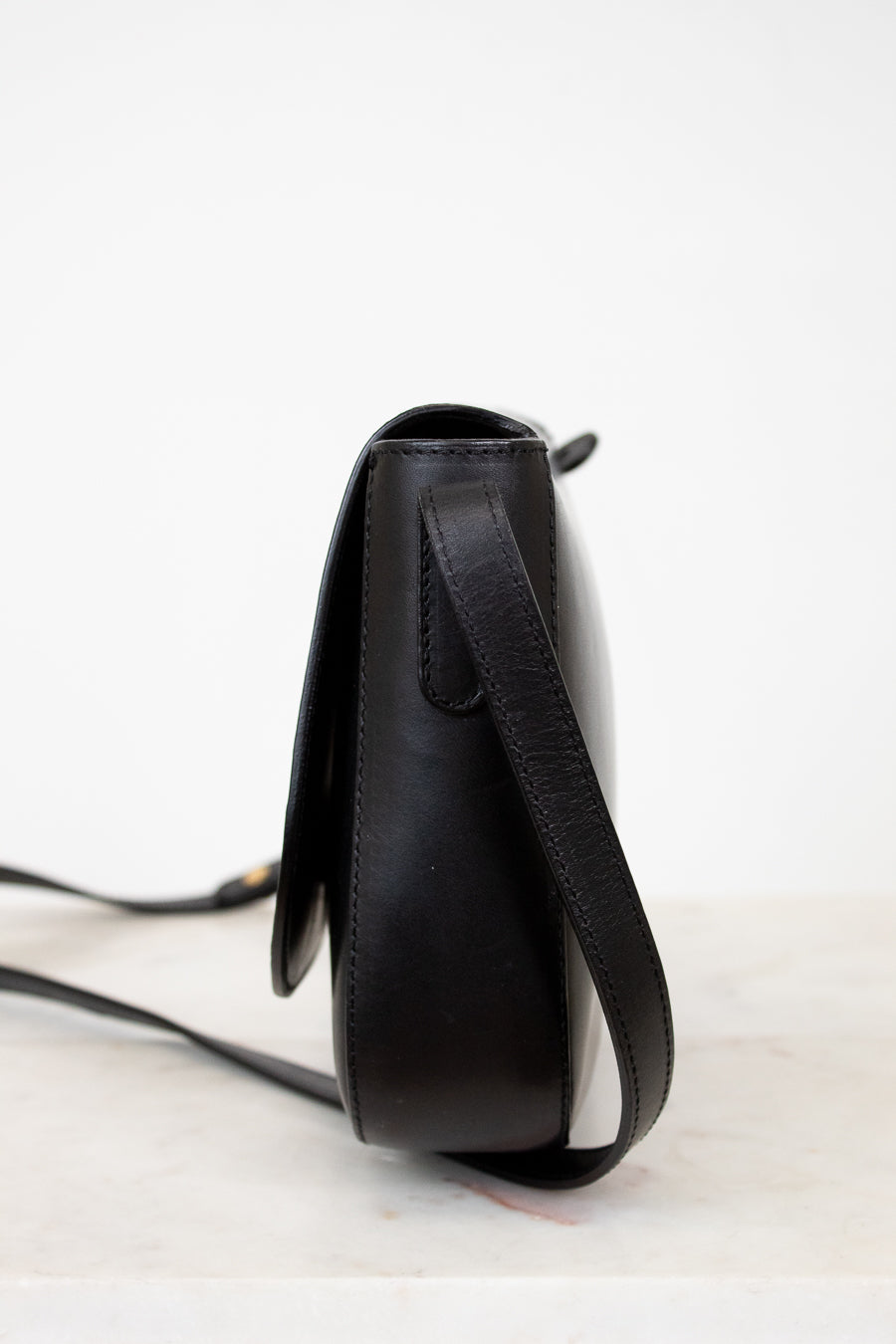 Black leather crossbody bag on a light gray background