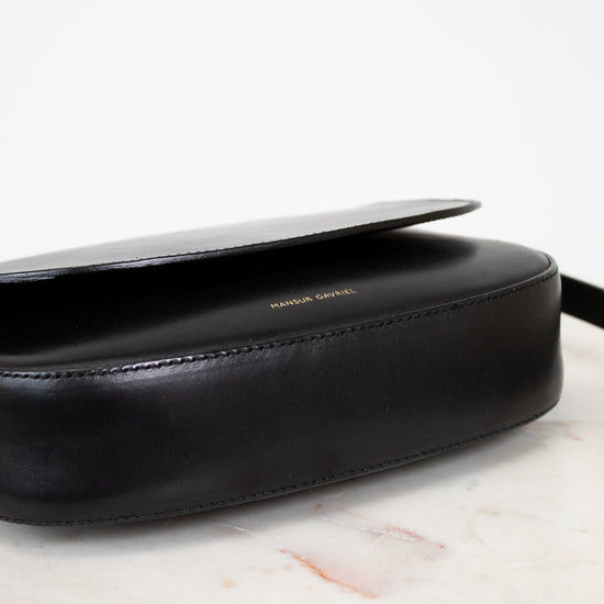 Black leather bag on a marble surface with a white background