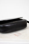Black leather bag on a marble surface with a white background