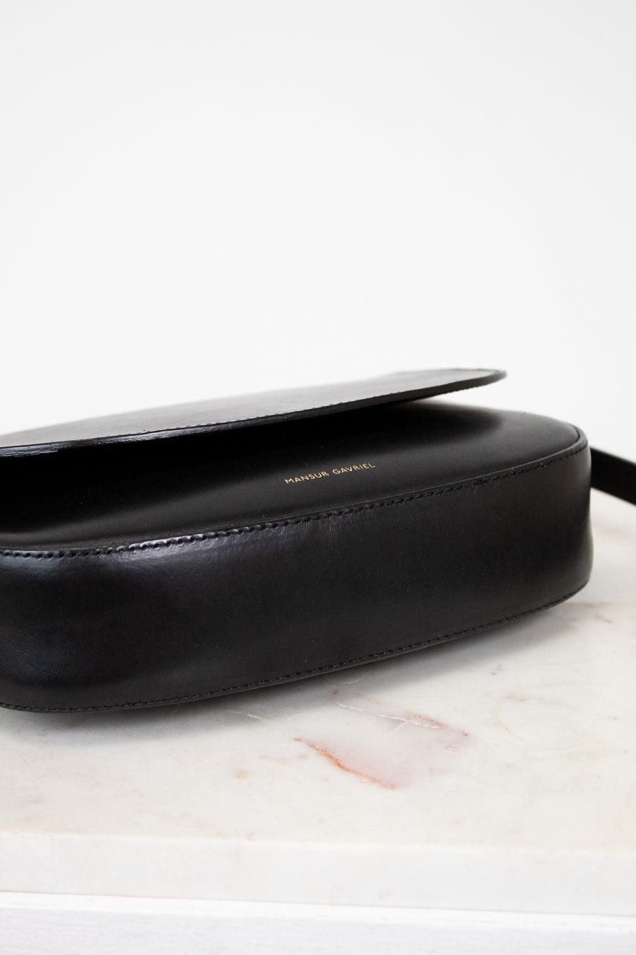 Black leather bag on a marble surface with a white background
