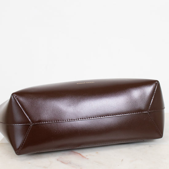 Brown leather shoulder bag on a light wooden surface