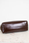 Brown leather shoulder bag on a light wooden surface
