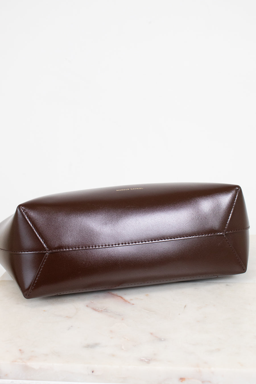 Brown leather shoulder bag on a light wooden surface