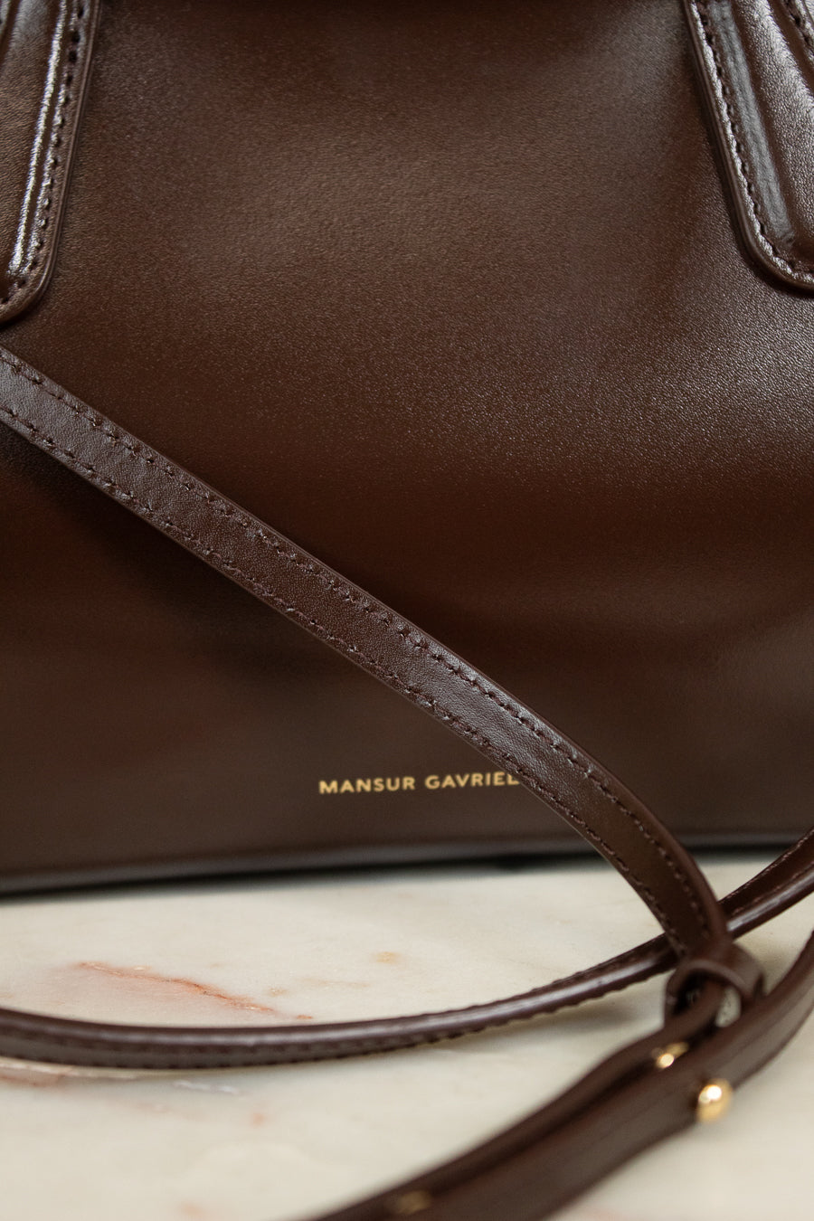 Brown leather handbag with visible brand name on a marble surface