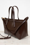 Brown leather handbag with a shoulder strap on a light background