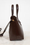 Brown leather handbag with gold clasp on a white marble surface