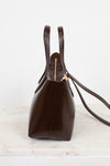 Brown leather handbag with gold clasp on a light marble surface