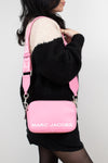 Person wearing a pink Marc Jacobs bag on a plain background