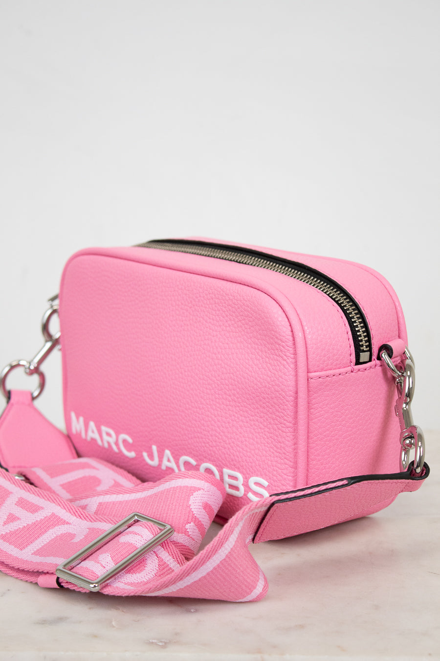 Pink handbag with visible 'Marc Jacobs' branding on a light background