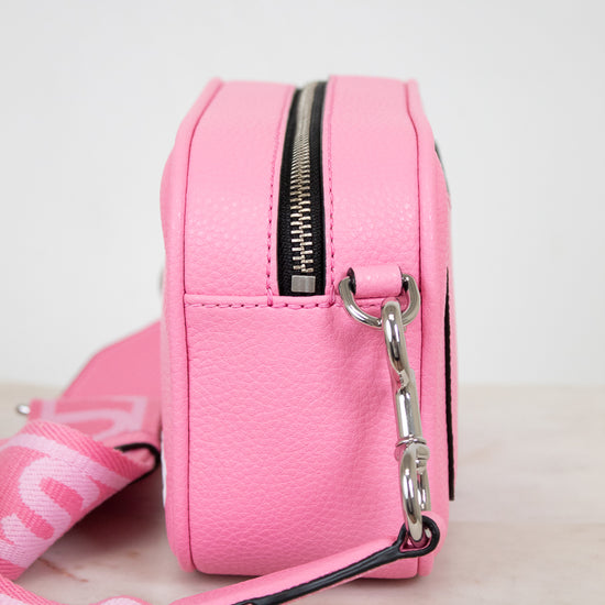 Pink crossbody bag with a strap on a light background