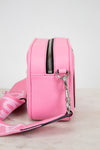 Pink crossbody bag with a strap on a light background