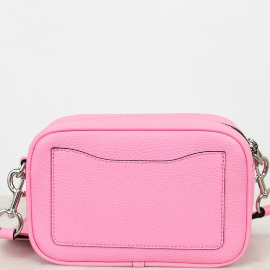 Pink crossbody bag on a light marble surface with a white background