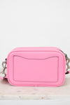 Pink crossbody bag on a light marble surface with a white background
