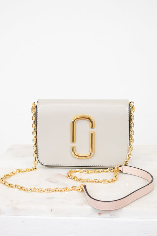 White handbag with gold chain and logo on a white background