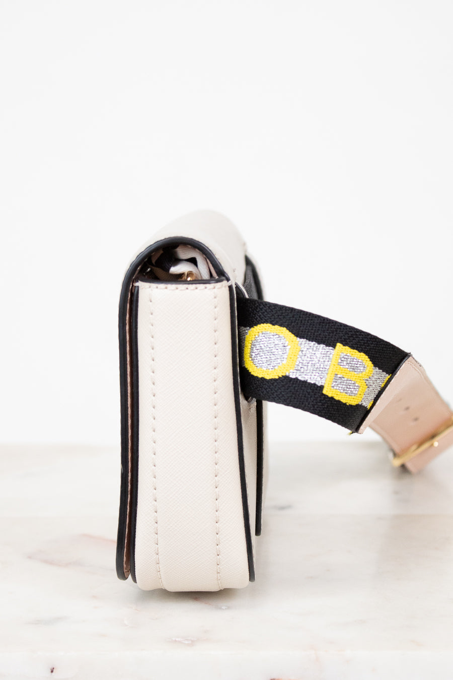 White purse with a black strap featuring yellow and gray accents on a white background