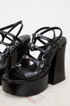 Black platform sandals with thin straps on a light background