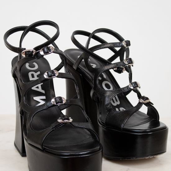 Black platform sandals with 'Marc' branding on a light background