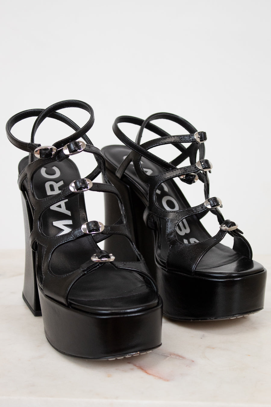 Black platform sandals with 'Marc' branding on a light background