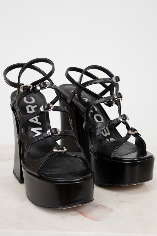 Black platform sandals with 'Marc' branding on a light background
