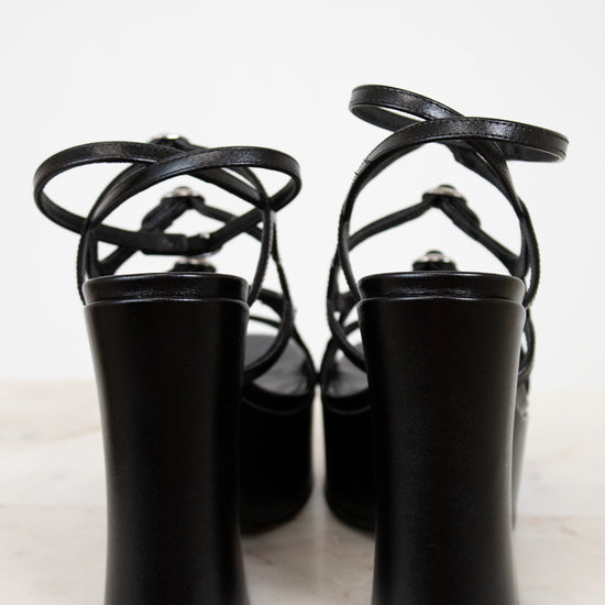 Black high-heeled shoes with strappy design on a white background