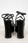 Black high-heeled shoes with strappy design on a white background