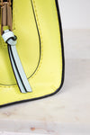 Close-up of a yellow handbag on a light marble background