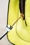Close-up of a yellow handbag with a gold zipper and black handle.