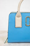 Blue handbag with beige handle and gold logo on a light background
