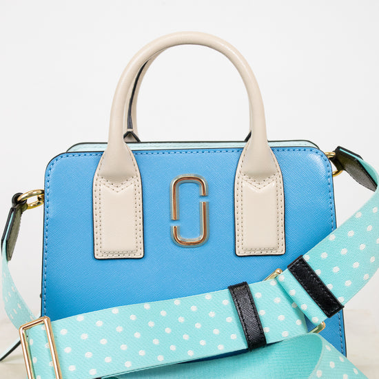 Blue handbag with a polka dot strap on a light background