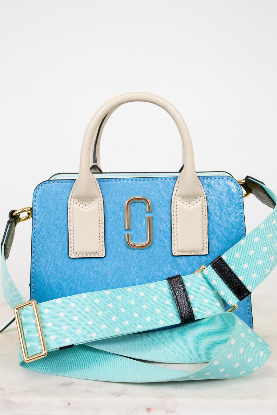 Blue handbag with a polka dot strap on a light background